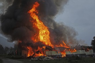 Flames and smoke rise from burning farm building