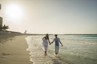 Couple of lovers walking hand in hand on caribbean beach at sunset