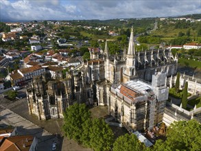 Gothic cathedral with cityscape in the background, some areas under construction, aerial view,