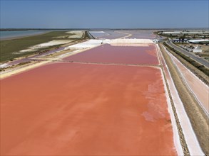 Aerial view of pink salt basin with surrounding infrastructure and flat, clear sky, Salinas de