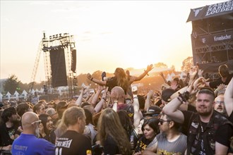 Crowdsurfers in front of the evening sun at the Wacken Open Air in Wacken. The traditional metal