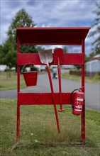 Red fire extinguishing point with fire extinguisher, shovel, spade and bucket at a campsite on Lake