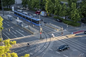 View from above of a road crossing with tram and tram stop, cyclist and a car crossing the
