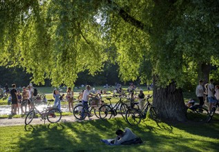 Large meadow at Schwabinger Bach, Many people on a summer day in the English Garden, Munich,