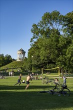 People playing volleyball in a meadow in the English Garden, people enjoying the summer day in the