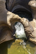 Water flowing through eroded rock formations, canyon with steep orange-coloured rock cliffs with