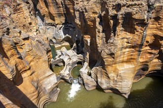 Eroded rock formations, canyon with steep orange-coloured rock cliffs with the Blyde River,