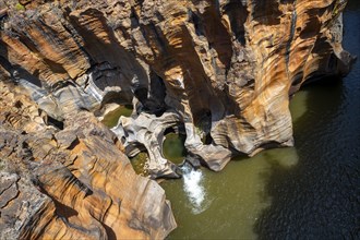 Eroded rock formations, canyon with steep orange-coloured rock cliffs with the Blyde River,