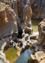 Eroded rock formations, canyon with steep orange-coloured rock cliffs with the Blyde River,