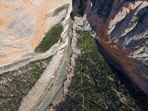 Deep gorge with steep, vegetation-rich rock faces and a river flowing through the narrow gorge,