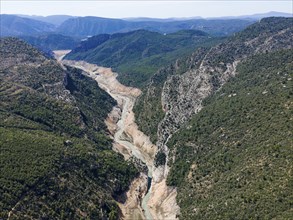 A narrow river flowing through a narrow gorge with high, wooded rock faces, aerial view, Congost de