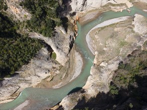 Expansive view of a river course running through a deep, forested gorge in a mountainous region,