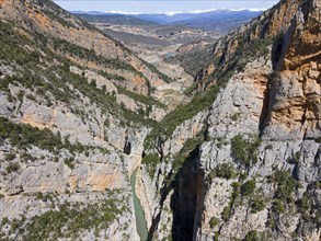 An aerial view of a rocky gorge in a mountainous environment with a river winding through rugged