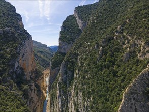 View of a river running through a mountainous region with rugged rock faces and lots of greenery,