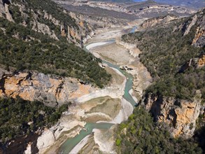 An aerial view of a rocky gorge with a winding river and densely overgrown cliffs, aerial view,