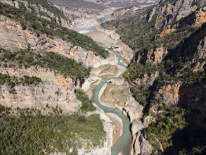 An aerial view of a deep gorge with a meandering river surrounded by steep cliffs and lush