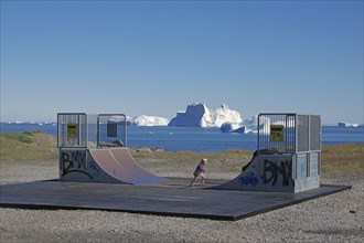 Halfpipe near a beach with icebergs in the sea and a BMX-riding kid, blue sky, end of the world,