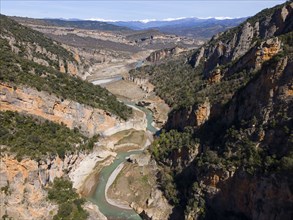 A river meanders through an extensive mountain landscape with deep canyons and lots of vegetation,