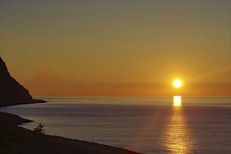 Sunset over the calm sea with a coastline and clear sky in the background, St. Lawrence River,