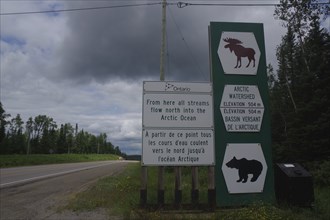 Road sign and traffic signs in a rural wooded area on a cloudy day, watershed, Manitoba, Canada,