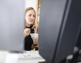 Food at work: A woman eats muesli with fruit in the office. Berlin, 25.07.2024