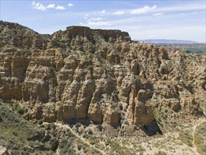 A rocky and hilly area with cliffs under a clear blue sky, aerial view, limestone tuff and loess