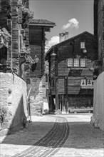 Paved footpath surrounded by old wooden houses, historic village centre, black and white