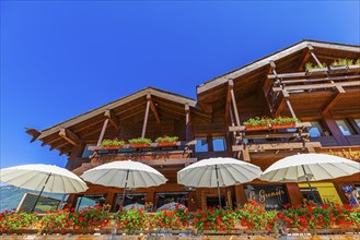 Modern chalet with terrace and white parasols, flower boxes in front of balconies, Grimentz, Val