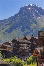 Nested old wooden houses in the historic centre of Grimentz, with the summit of the Scex de Marenda