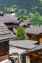 Old wooden houses with wooden shingle roofs in the historic centre of Grimentz, behind the church