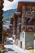 Paved footpath surrounded by old wooden houses, flower boxes on balconies and windows, historic