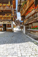 Paved footpath surrounded by old wooden houses, flower boxes on balconies and windows, historic