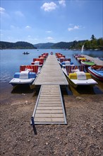 A picturesque scene with colourful pedal boats and wooden boats on a jetty in front of the