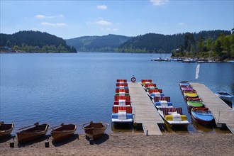 A picturesque scene with colourful pedal boats and wooden boats on a jetty in front of the