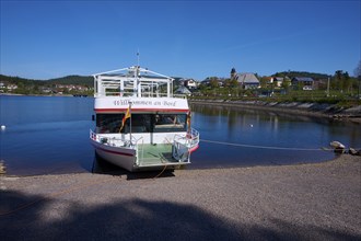 A boat with the inscription 'Welcome aboard' is anchored at the Schluchsee, in the background you