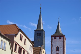 Two church towers and buildings in front of a blue sky in a cityscape, Karlstadt, Main Spessart,