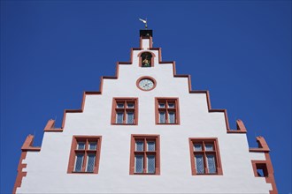 Karlstadt Town Hall, Historic building facade with red details and a clock under a clear blue sky,