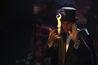 A street magician manipulates a ball of flame for an illusion during a stage performance