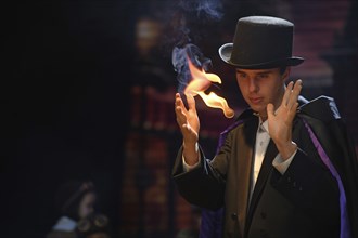 A street magician manipulates a ball of flame for an illusion during a stage performance