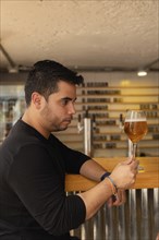 A Latino man in profile, looking appreciatively at his craft lager beer. The image captures his