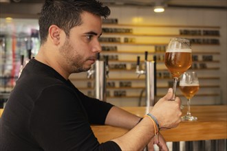 A Latino man savoring a craft lager beer, enjoying its rich flavor and quality. The image captures