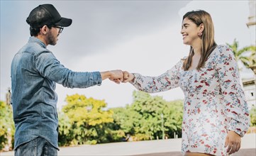 Man and girl shaking hands on the street. Two young smiling teenagers shaking hands in the street