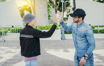 People greeting each other and shaking hands on the street. Two teenage friends shaking hands