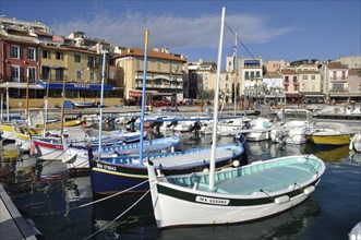 Colorful boats in a vibrant harbor with Mediterranean-style buildings under a clear blue sky,