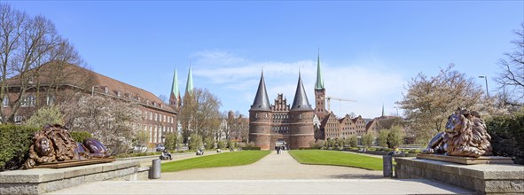 Wide panorama of the Lubeck Holstentor or Holsten gate park with two lion sculptures in front of