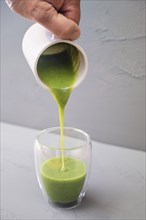 Green smoothie or soup made from wild herbs and vegetables is poured into a double-walled drinking