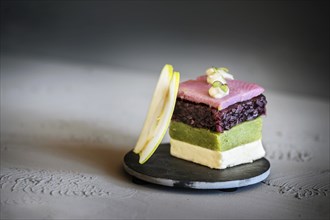 Fish appetizer, layered dish from square-cut pink soused herring, red onion, cucumber, cream