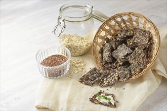 Crunchy snacks from linseed, oat flakes and various seeds in a basket, one with butter and parsley