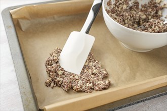 Dough made from flaxseed and oat flakes is spread on a tray with baking paper to make healthy