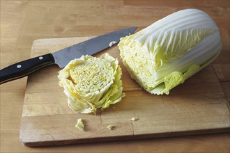 Cut slice of raw Chinese or napa cabbage on a wooden board and a kitchen knife, vegetarian cooking